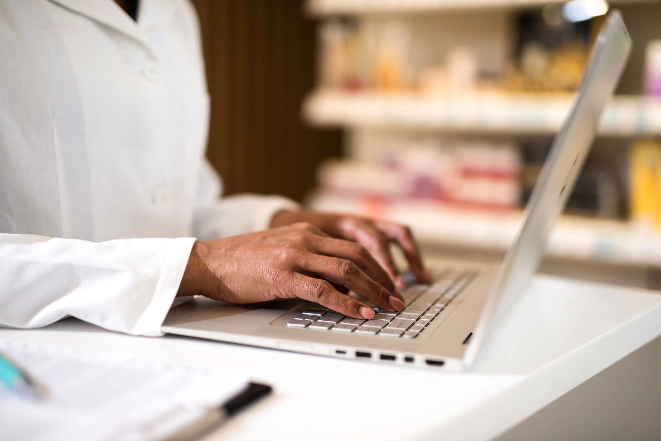 Pharmacist typing on a laptop for workflow and reporting tasks