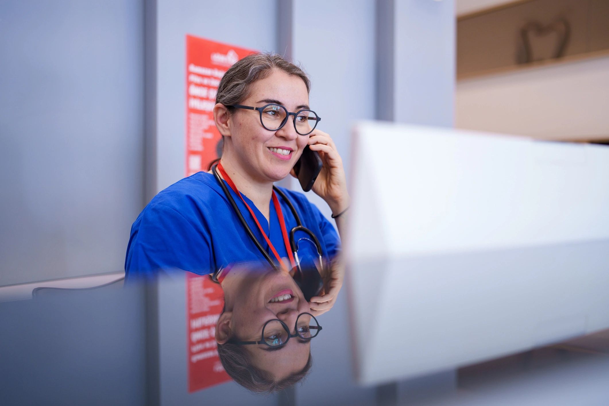 Healthcare admin support professional working at desk on phone and computer